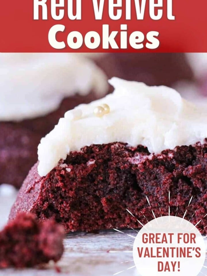 Red velvet cookie with vanilla buttercream frosting and white sprinkles split open to show the soft chewy center.