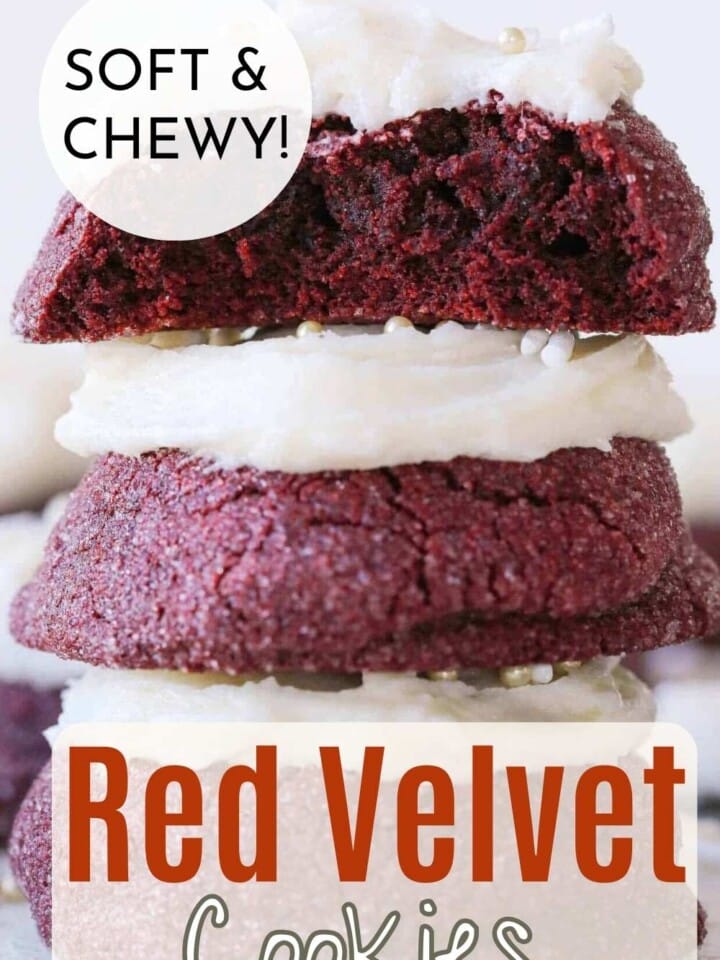 Red velvet cookies with vanilla buttercream frosting stacked and showing soft chewy centers.