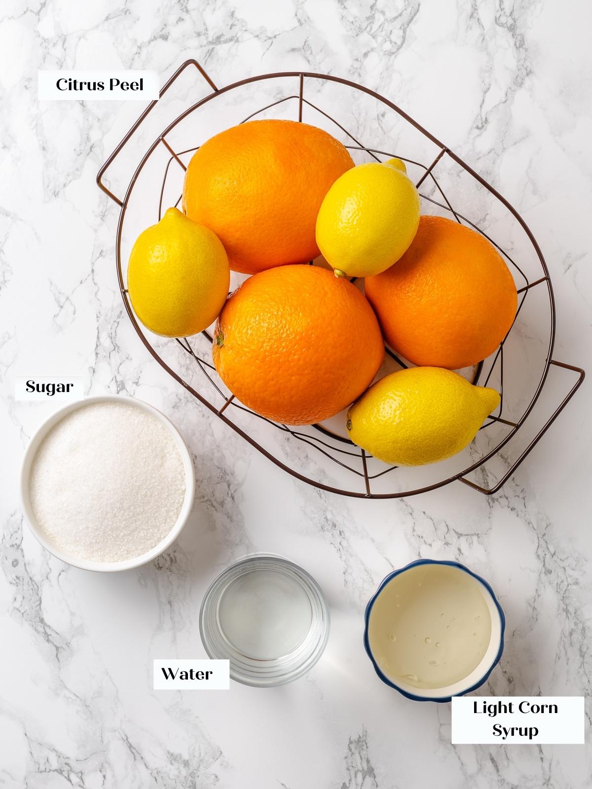 Citrus peels, sugar, corn syrup, and water measured on countertop before cooking.