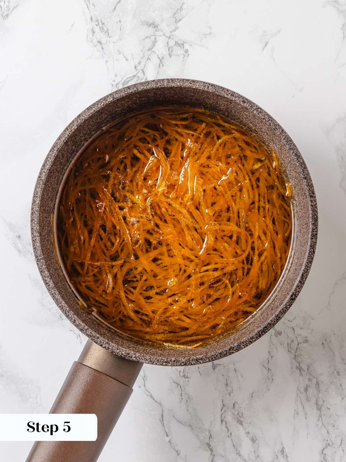 Orange peel simmering gently in sugar syrup until translucent and tender.