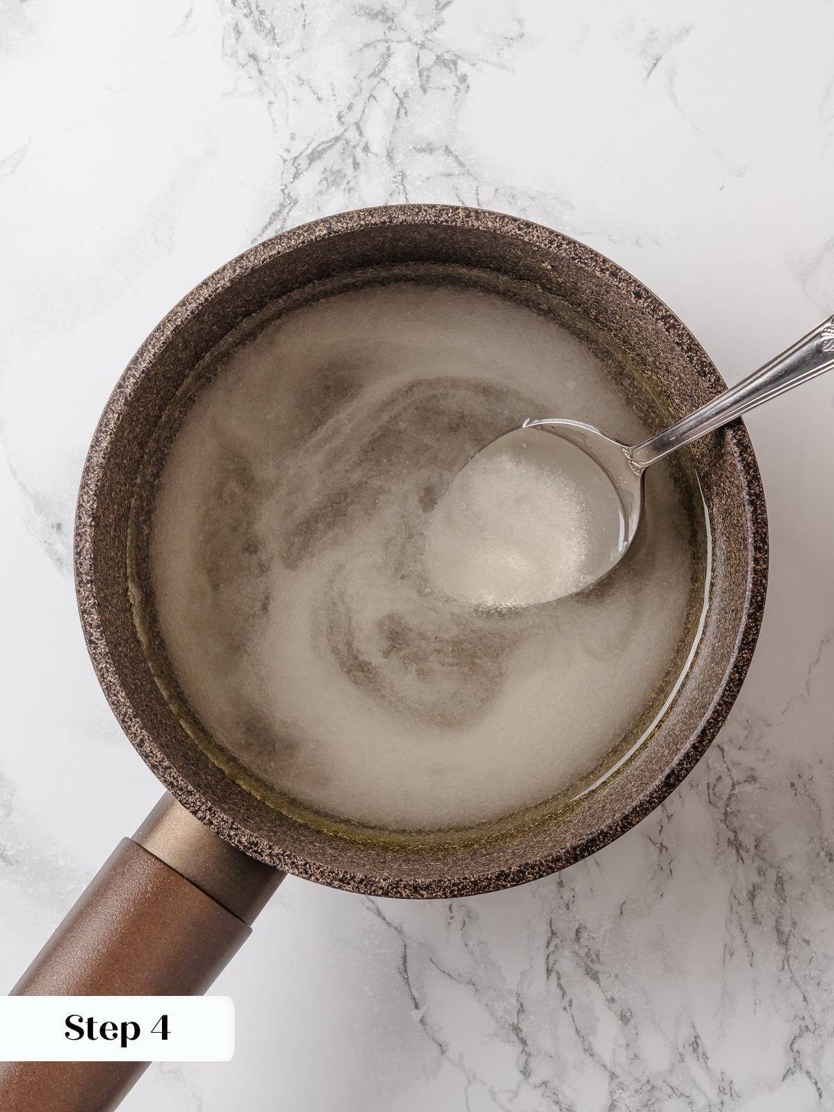 Sugar and water dissolved together in a pot to form clear simple syrup.