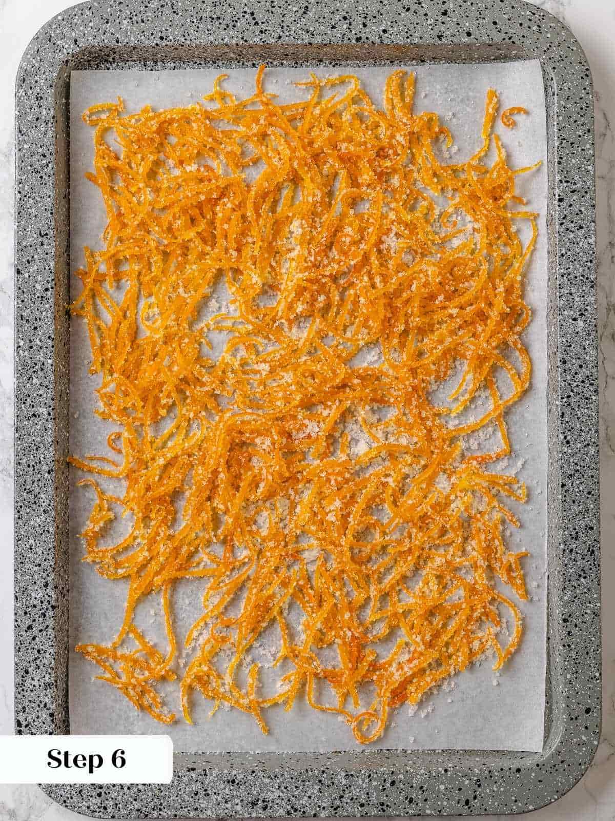 Candied citrus peel cooling on a pan after being tossed in sugar.