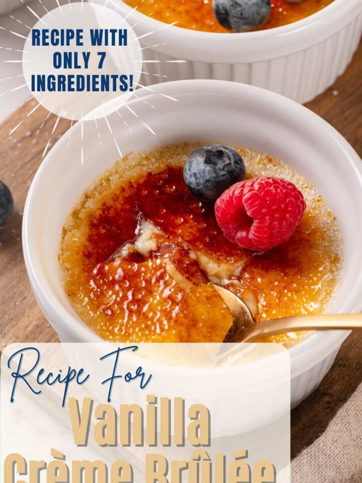 Vanilla crème brûlée with a cracked caramelized sugar top, garnished with a raspberry and blueberries. Text overlay reads Recipe with only 7 ingredients.