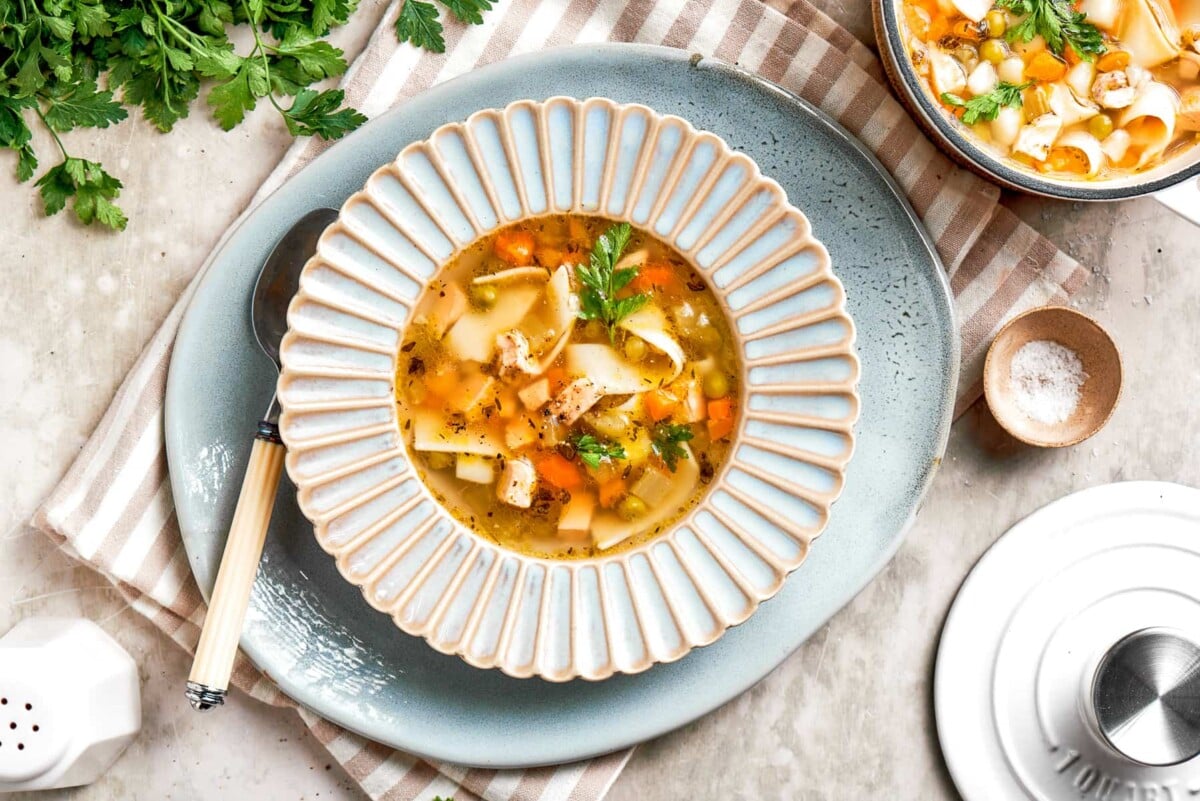 Chicken noodle soup in a bowl set on a rustic table.