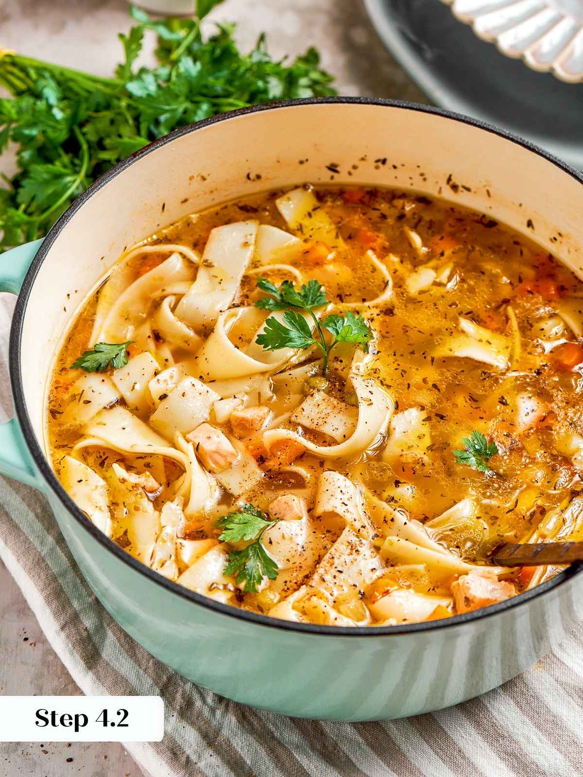 Fresh herbs sprinkled over finished chicken noodle soup.