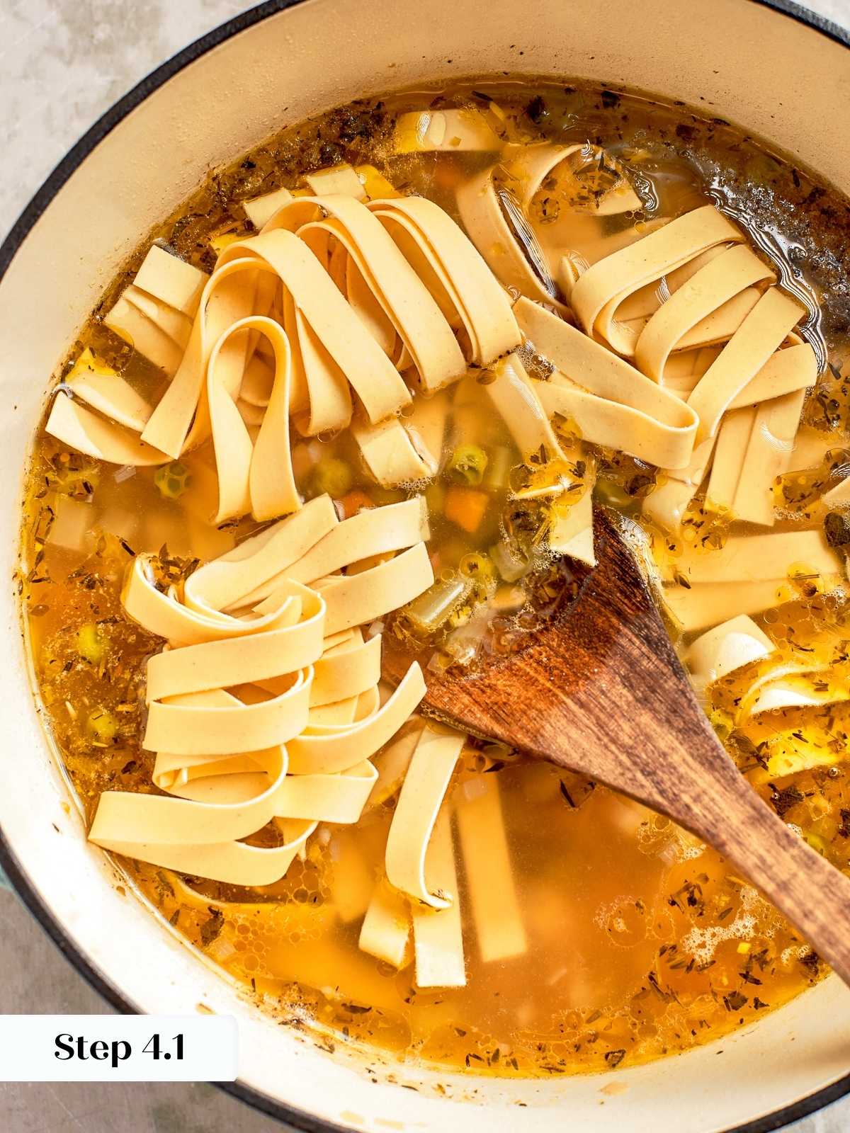 Egg noodles added to simmering soup during final step.