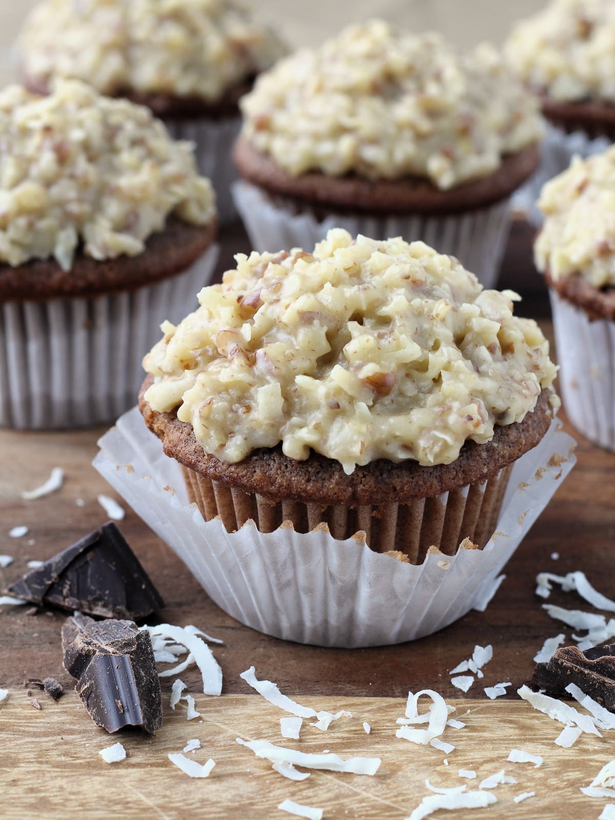 Piece of Baker&rsquo;s German chocolate resting beside frosted cupcakes.