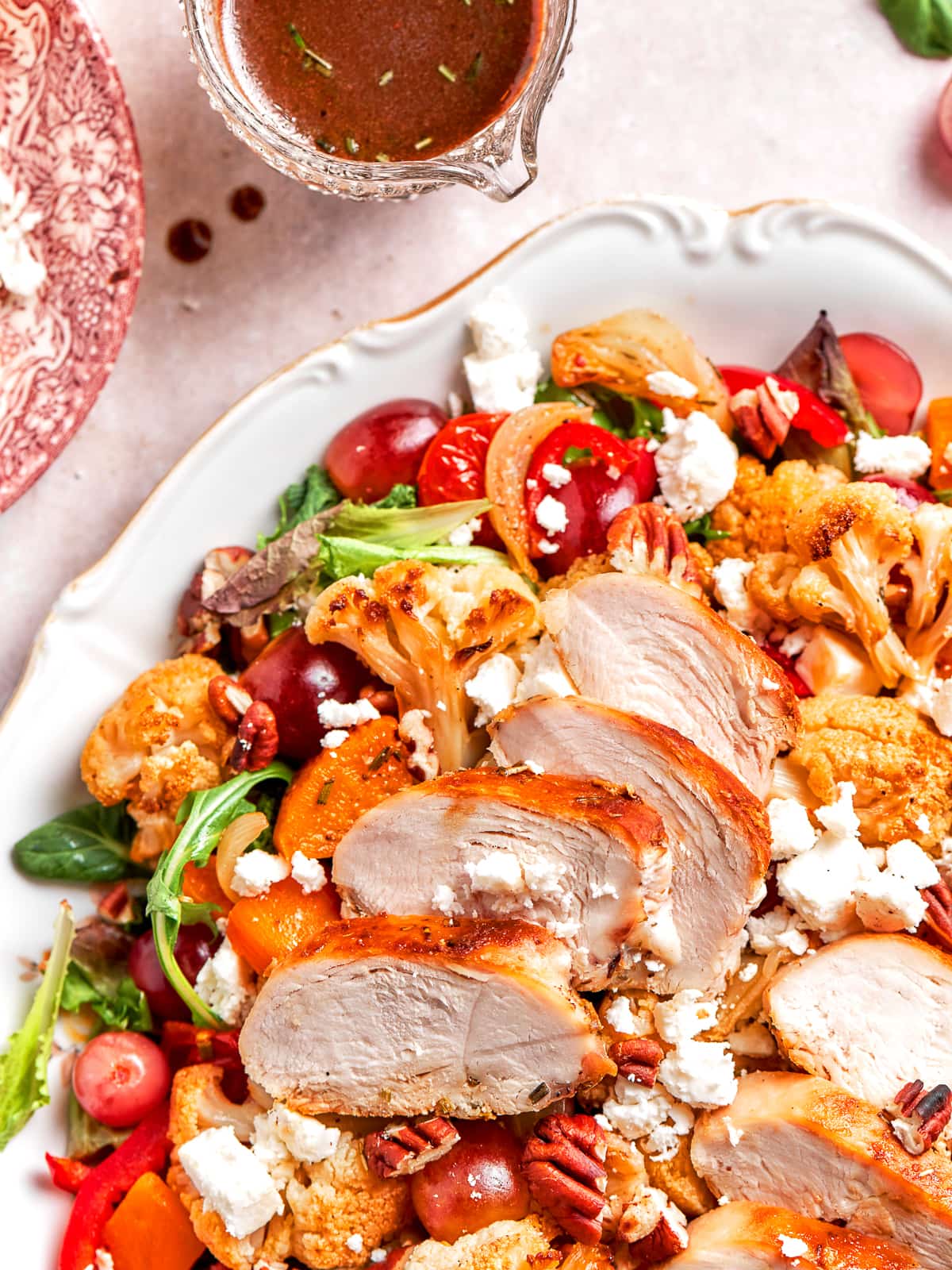 Small pitcher of vinaigrette next to fresh green salad.