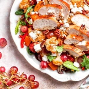 Fresh red grapes nestled among caramelized vegetables and greens.