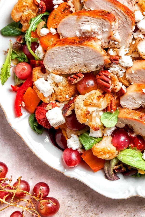 Fresh red grapes nestled among caramelized vegetables and greens.