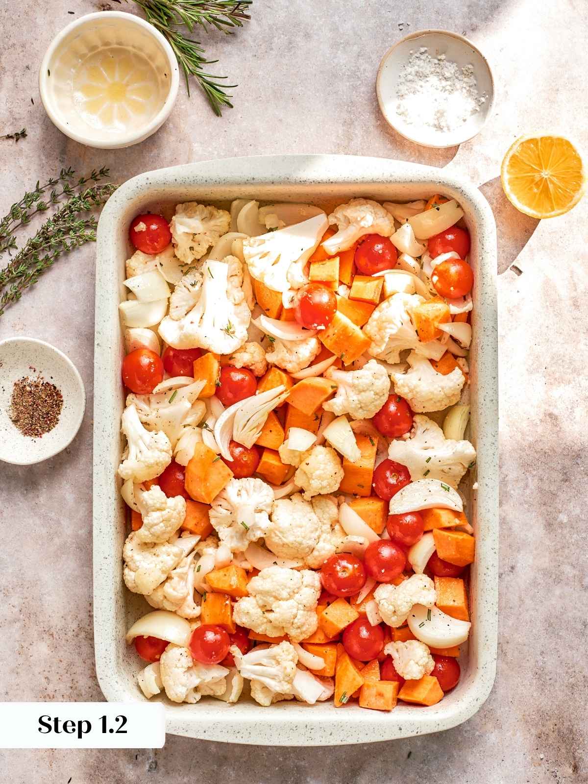 Unbaked cauliflower and sweet potatoes arranged evenly before roasting.