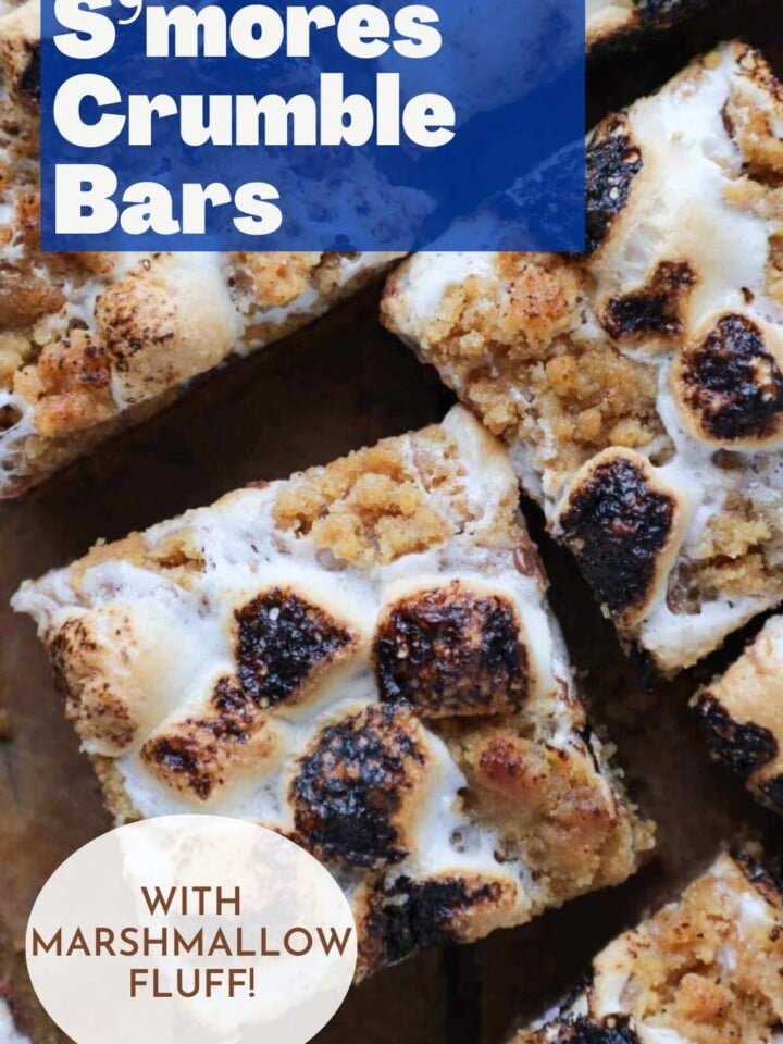 Tray of S'mores crumble bars with melty toasted marshmallows on top. Text overlay reads soft and chewy.