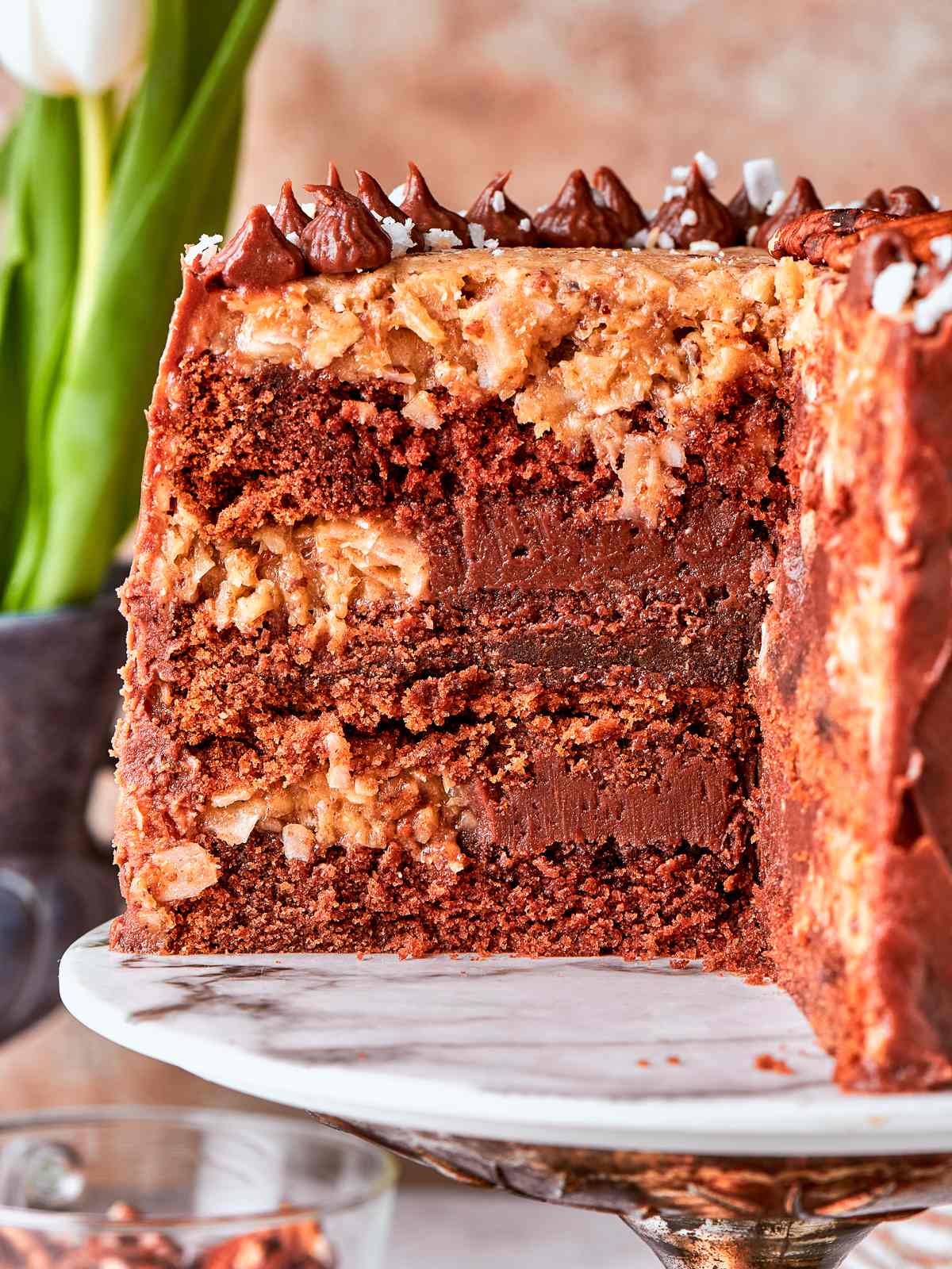 German chocolate cake displayed on marble cake stand with rustic topping.