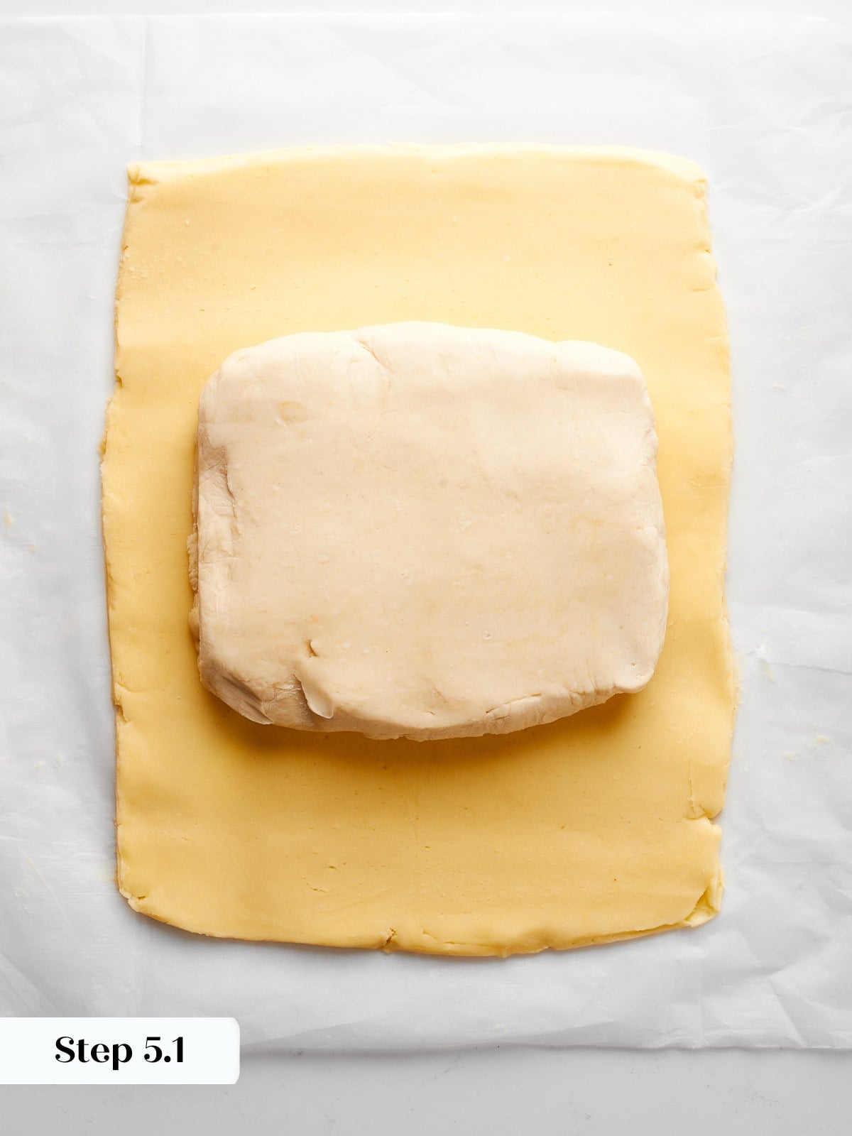 Dough positioned under butter block, aligned for enclosing and beginning inverse puff pastry.