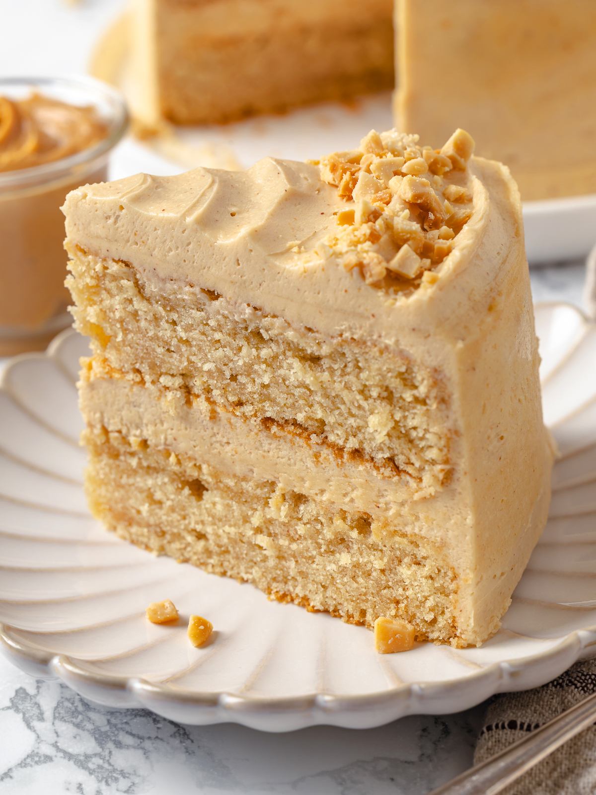 Slice of cake topped with thick fluffy peanut butter buttercream frosting.