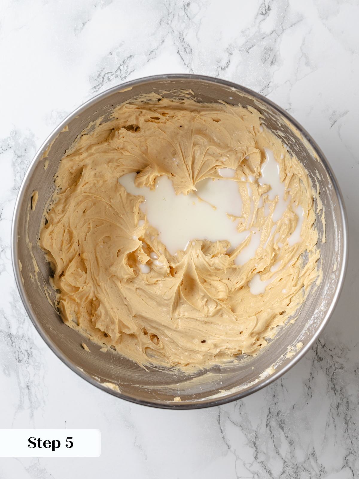 Cold heavy cream poured into frosting mixture before whipping light peanut butter buttercream.
