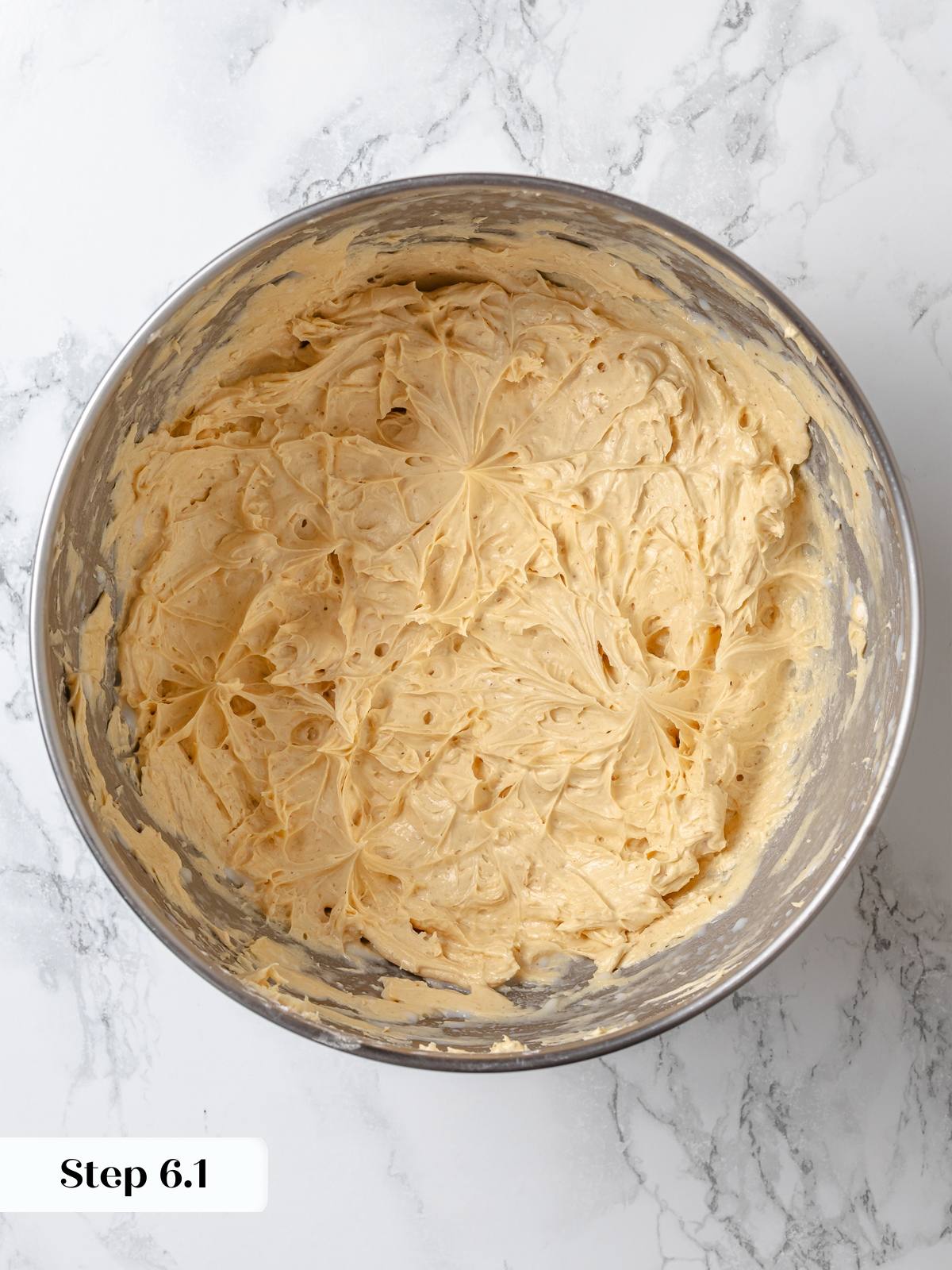 Peanut butter buttercream freshly whipped in metal mixing bowl with airy texture.