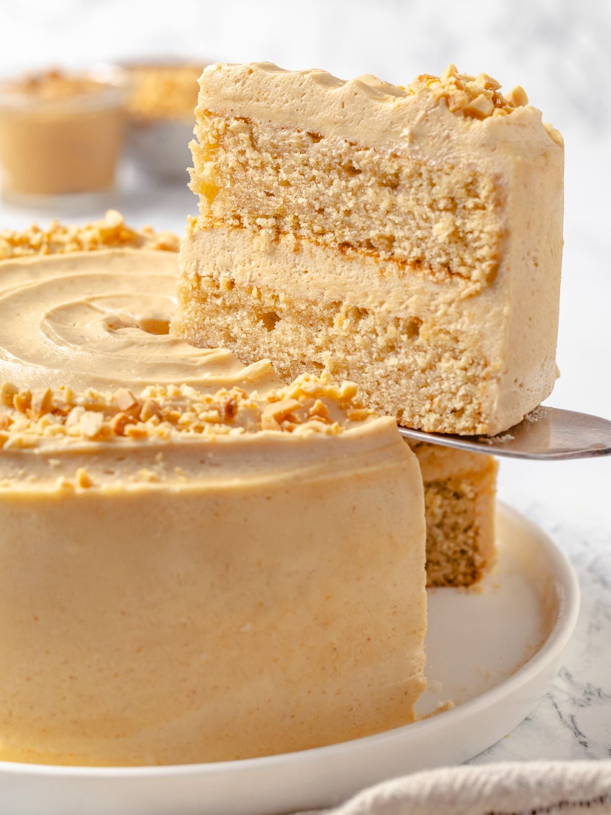 Cake server lifting slice of peanut butter layer cake.