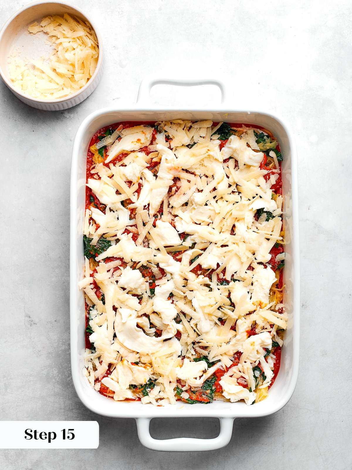 Shredded mozzarella sprinkled over sauce layer before baking spaghetti squash lasagna.
