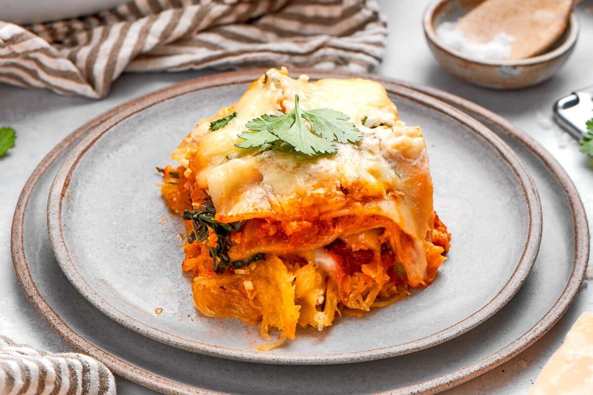 Vegetable-packed lasagna layers highlighting squash strands, greens, and tomato sauce.