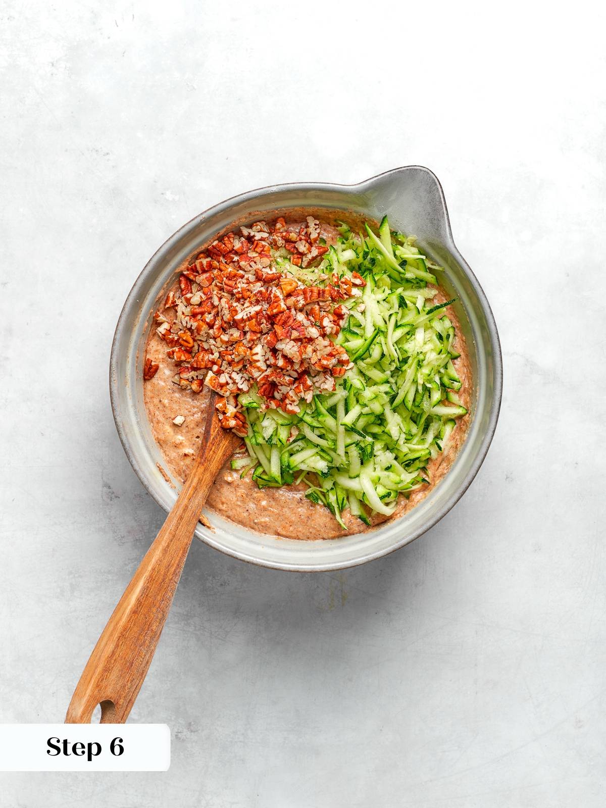 Mixing zucchini and pecans into batter for zucchini muffins.