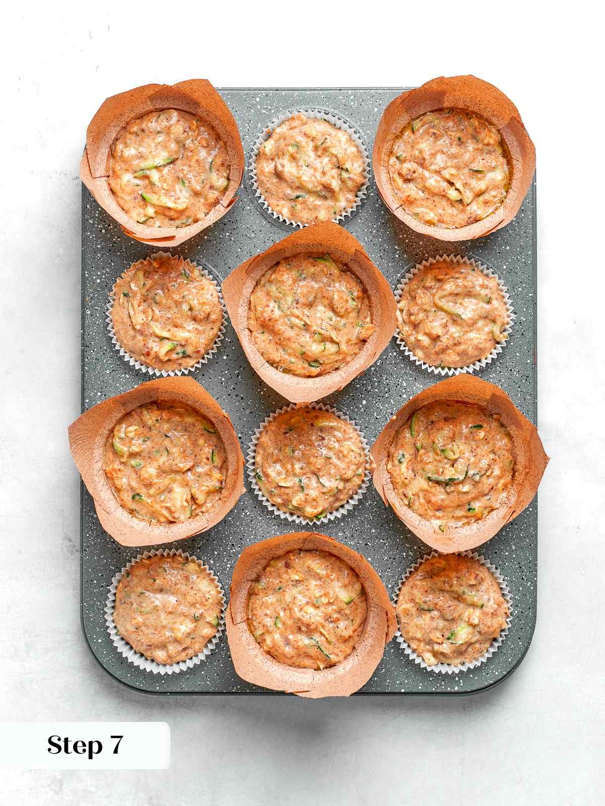 Zucchini muffin batter scooped into lined muffin cups ready for baking.