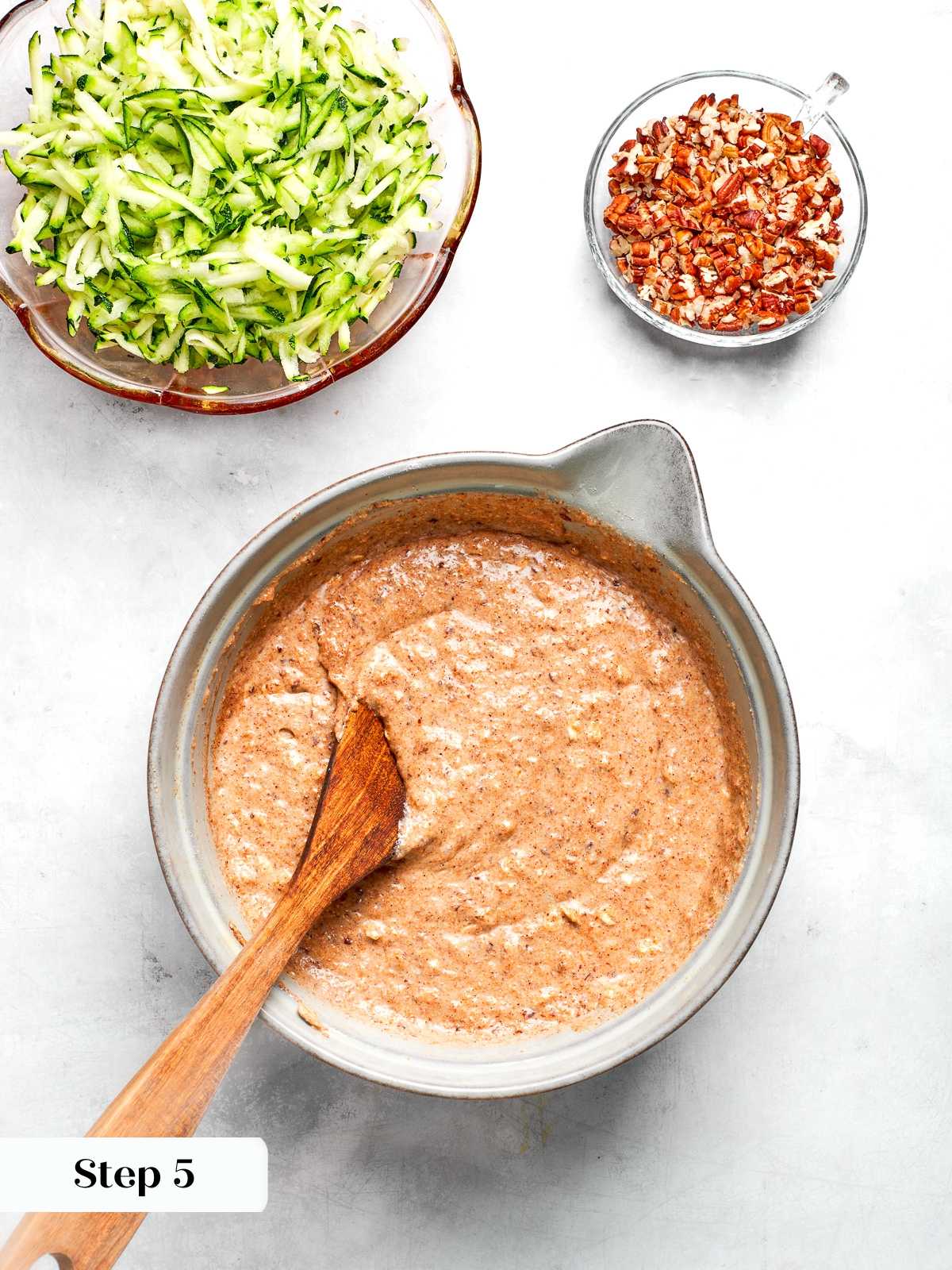 Mixing wet and dry ingredients together to form zucchini muffin batter.