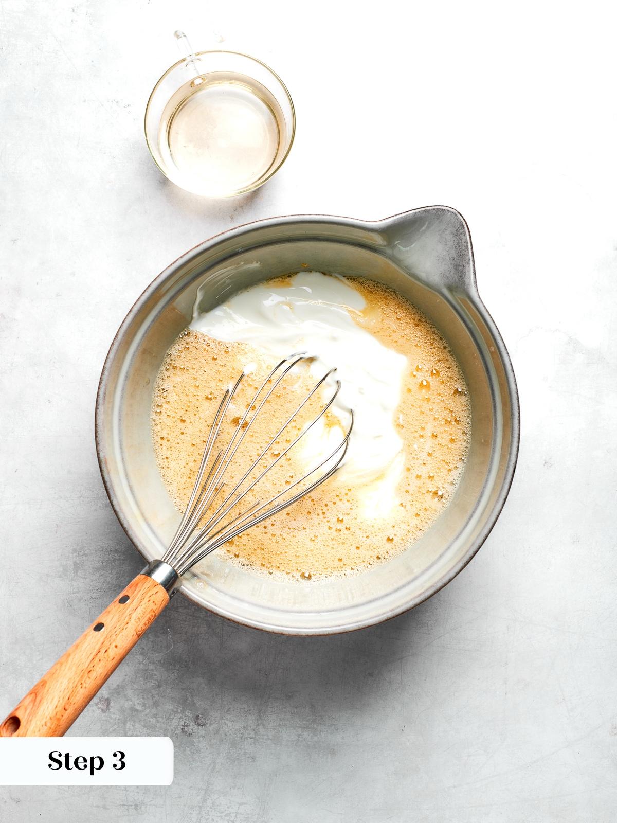 Wet ingredients including yogurt maple syrup and egg whisked together for muffin batter.