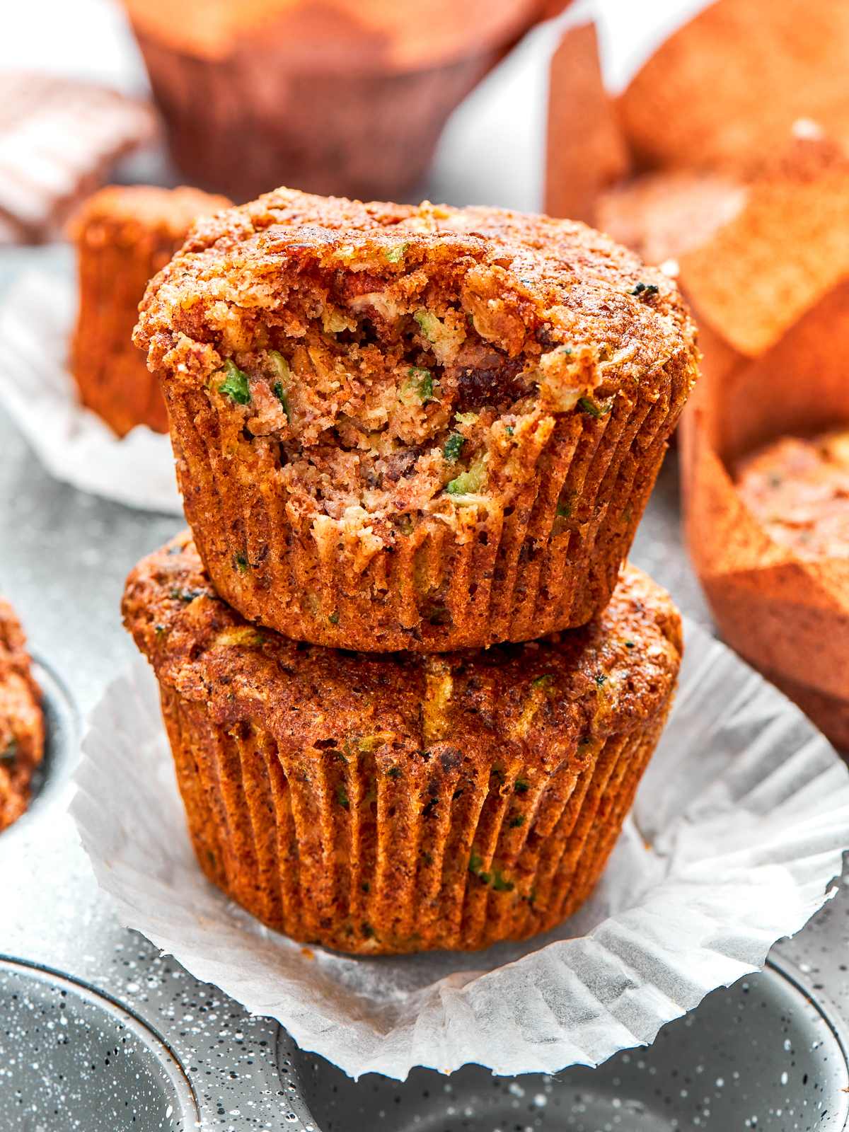 Stack of zucchini muffins with golden tops and tender crumb.