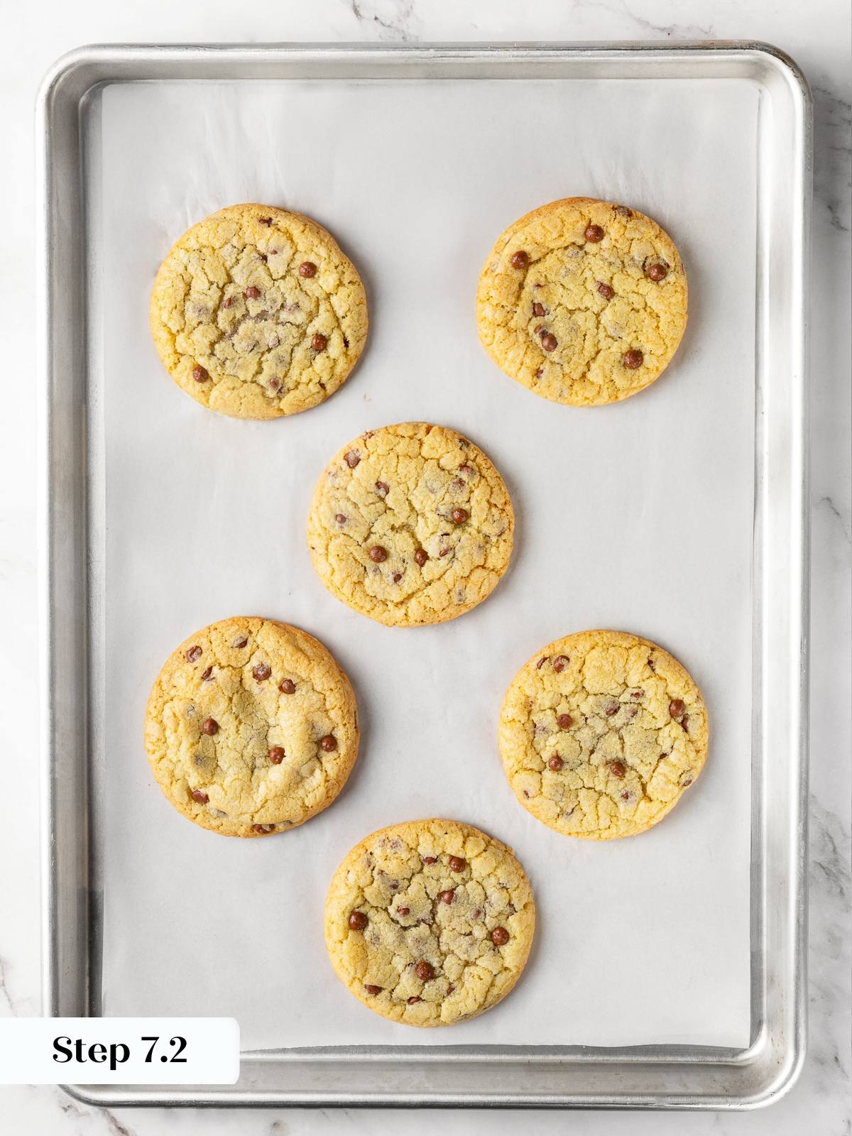 Freshly baked cookies on parchment-lined baking sheet with golden edges and soft centers.