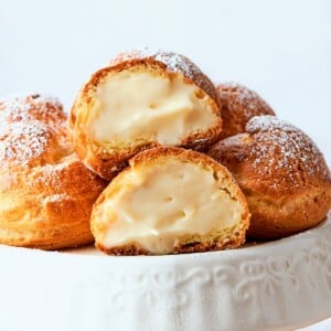 Golden cream puffs filled with light crème légère arranged on a serving plate.