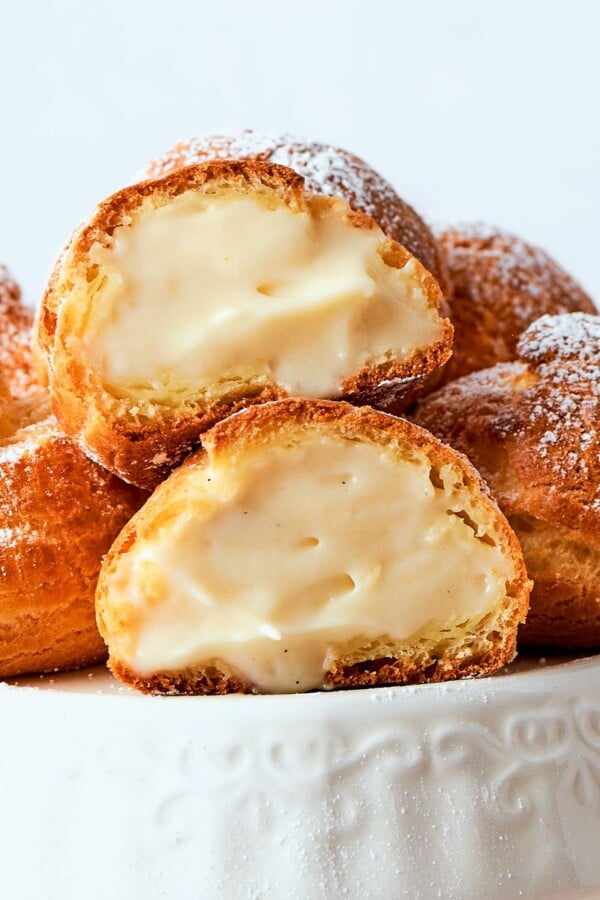 Golden cream puffs filled with light crรจme lรฉgรจre arranged on a serving plate.