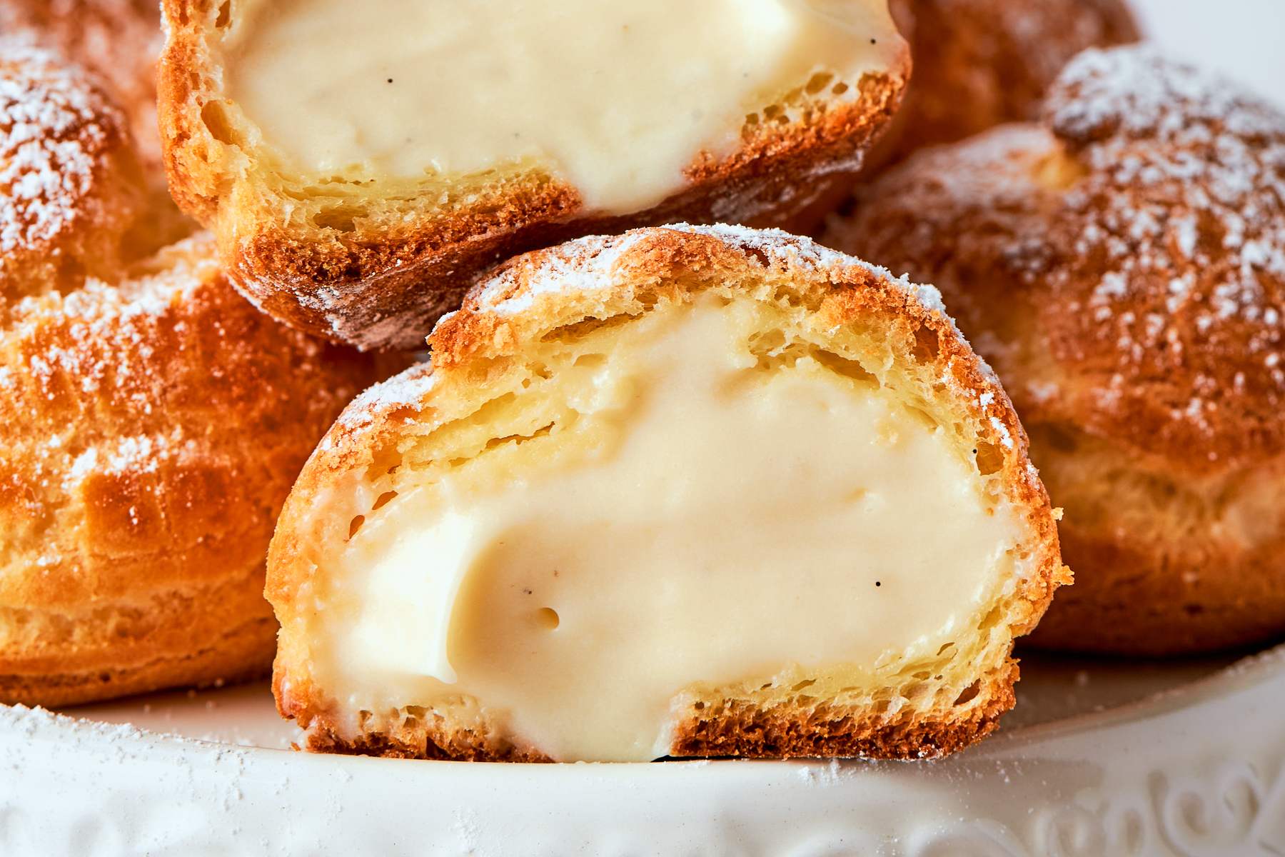 Vanilla cream puffs filled with crème légère arranged and lightly dusted with sugar.