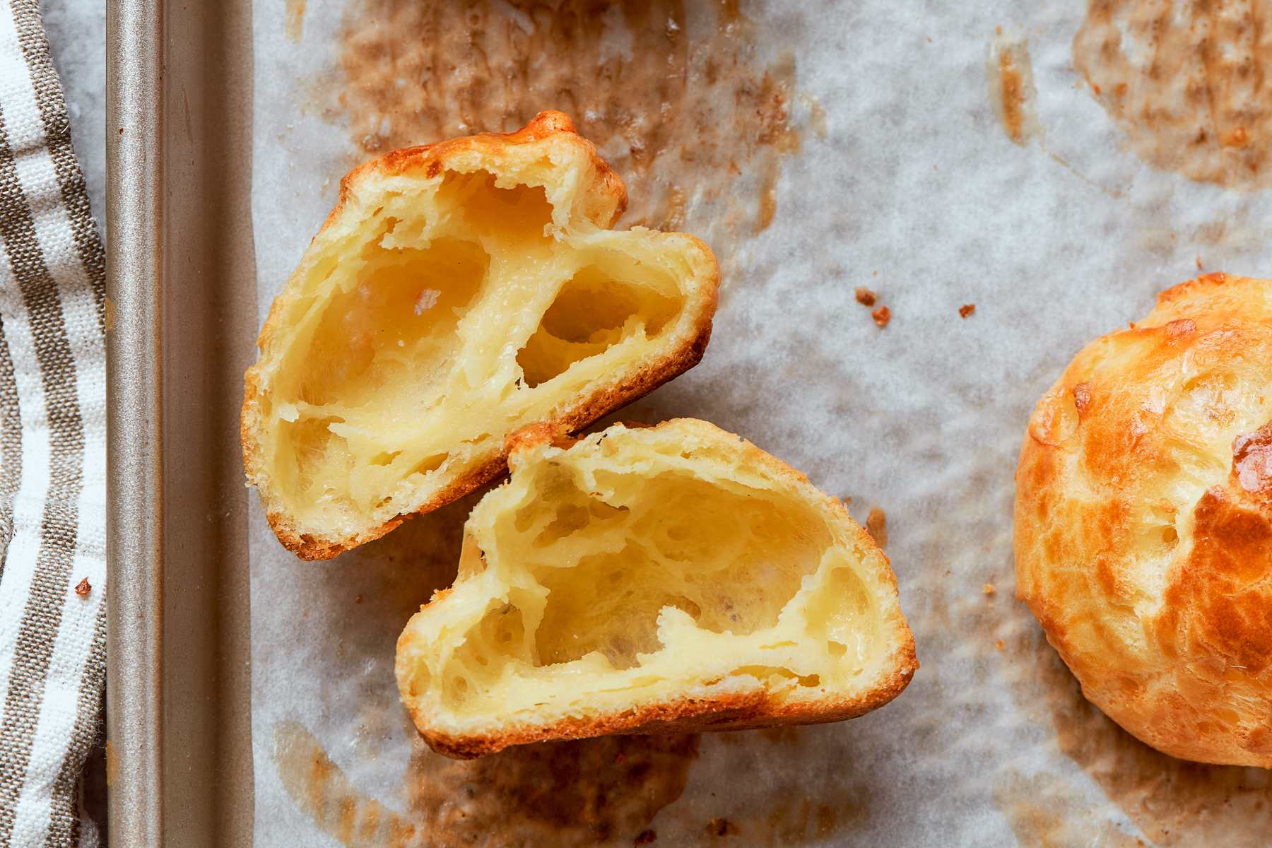 Gougère sliced cleanly in half showing hollow center and tender interior crumb.