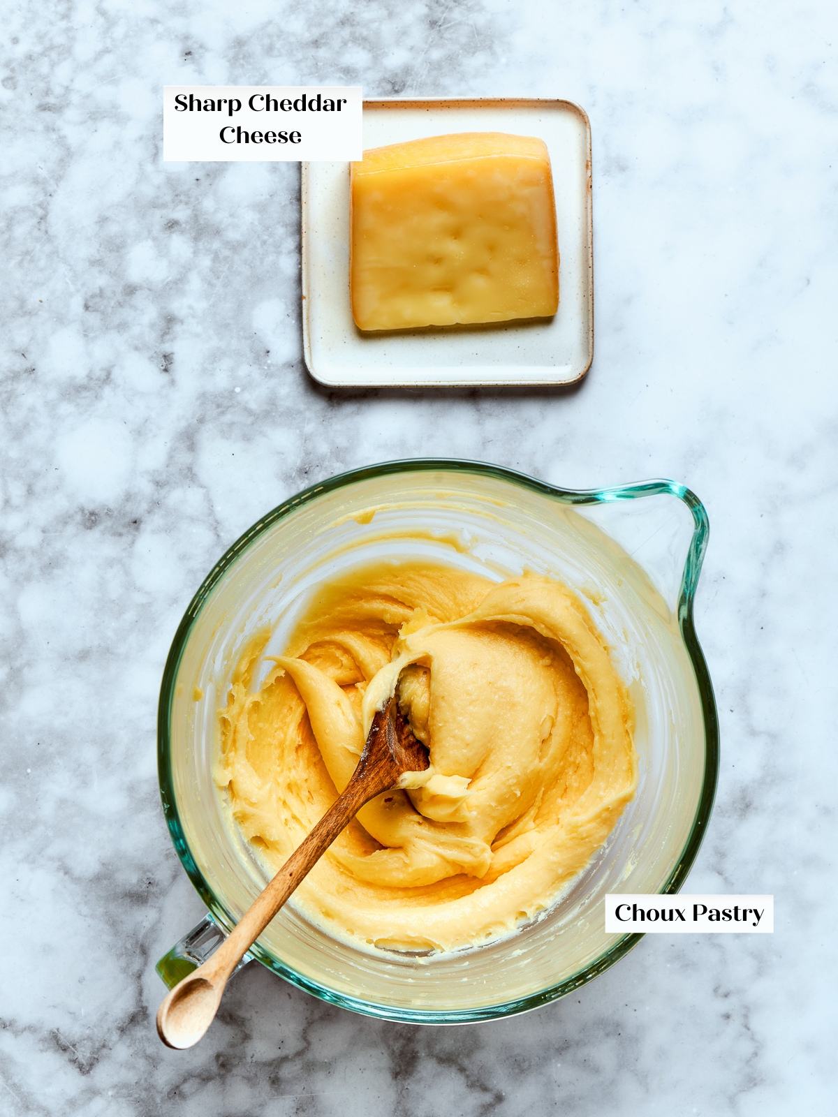 Shredded cheese and prepared choux dough set on countertop ready for mixing.