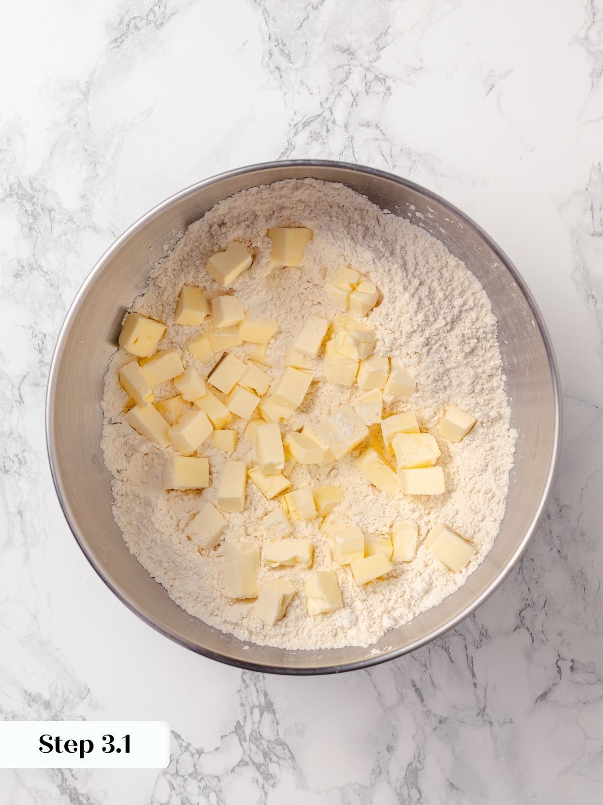 Butter being cut into flour mixture until small pieces are fully incorporated and coated.