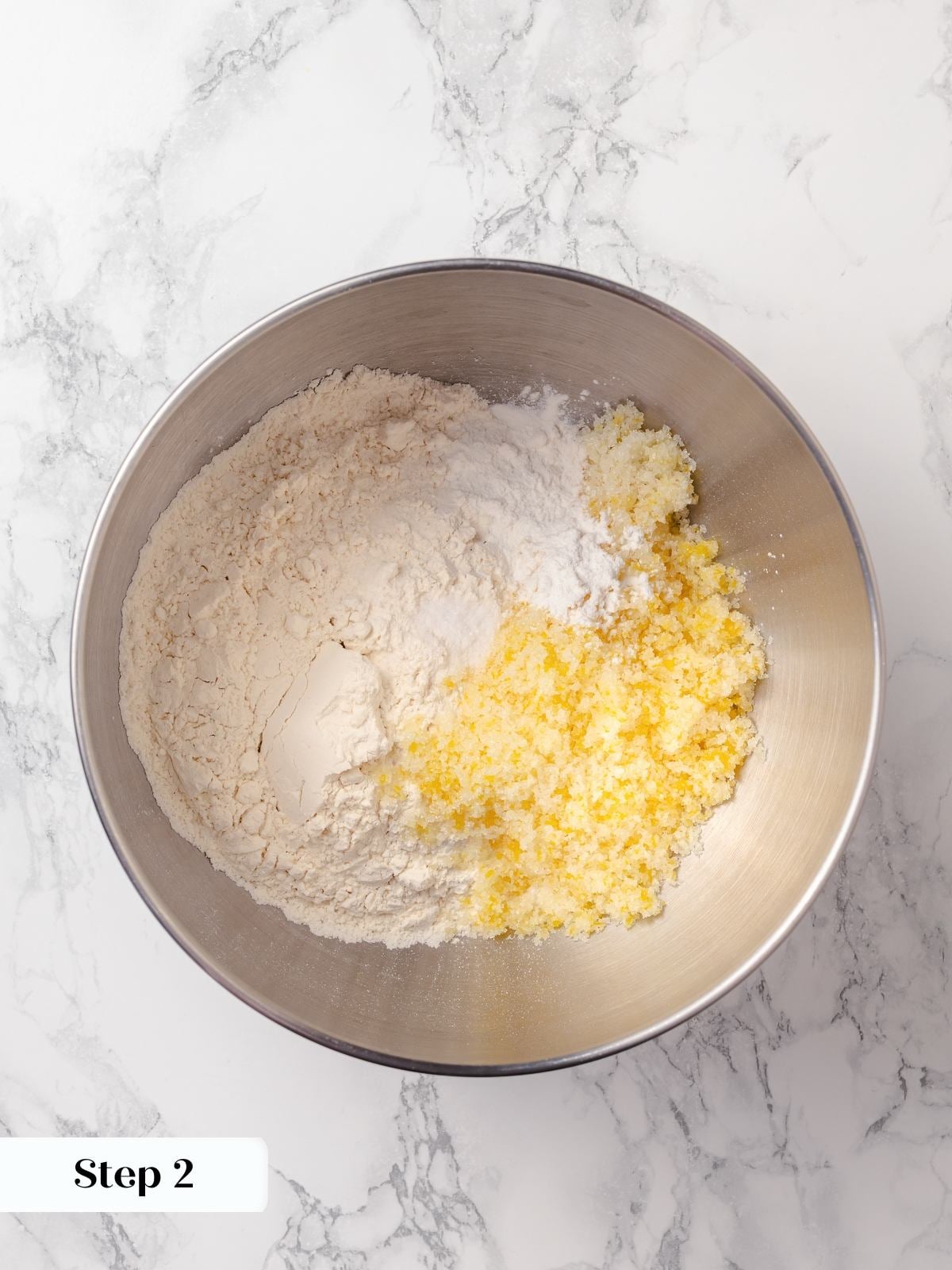 Dry ingredients combined in bowl including flour, sugar, baking powder, and lemon zest.