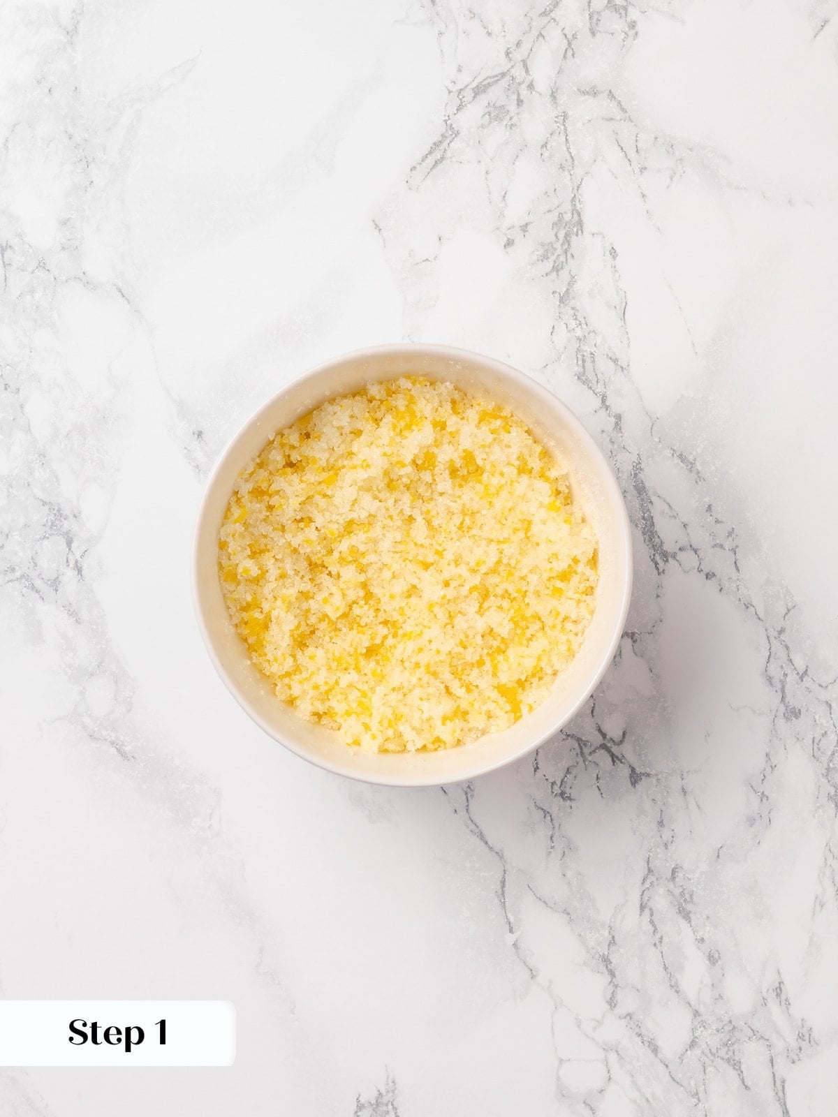 Lemon zest mixed into sugar releasing oils and creating fragrant citrus-infused sugar base.