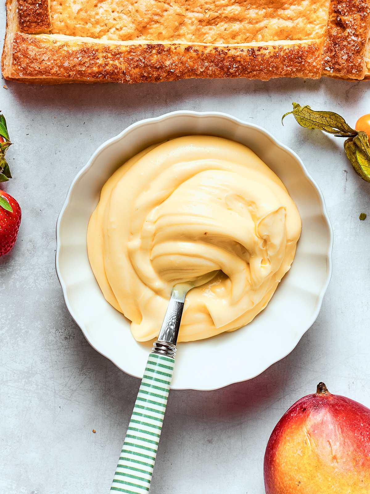 Bowl of pastry cream resting on countertop, showing smooth and creamy texture.