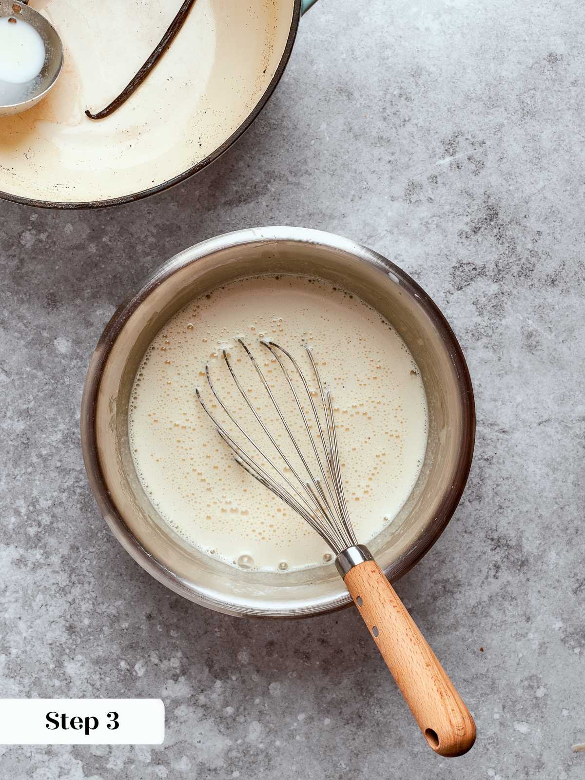Hot milk being poured into egg mixture while whisking to temper safely.