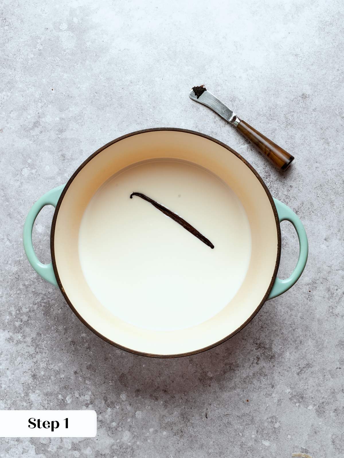 Milk and vanilla heating in a pot until steaming, preparing for tempering eggs.