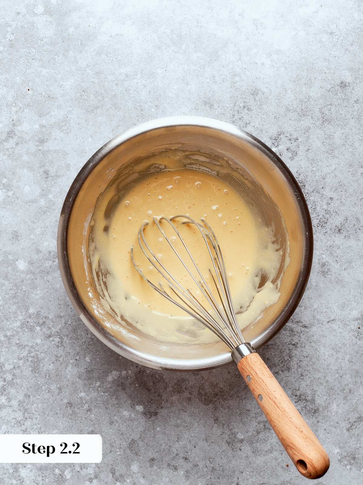 Fully whisked egg and sugar mixture appearing smooth and slightly pale before cooking.