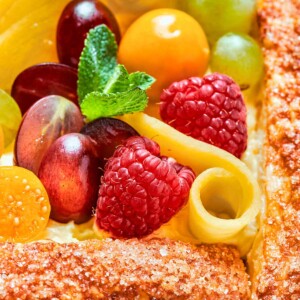 Tart topped with sliced mango arranged in decorative pattern over pastry cream.