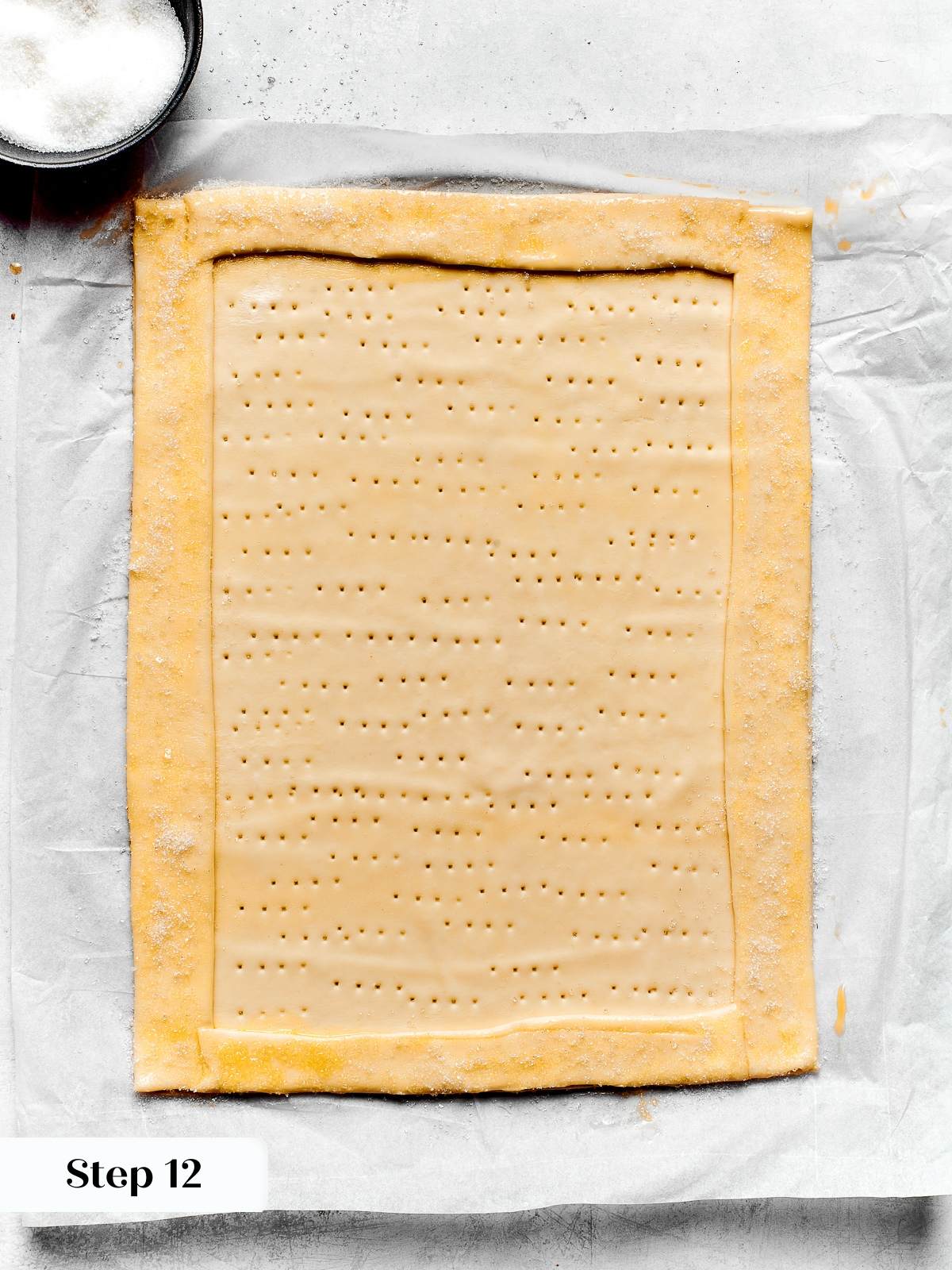 Puff pastry border brushed with egg wash and sprinkled with sugar before baking.