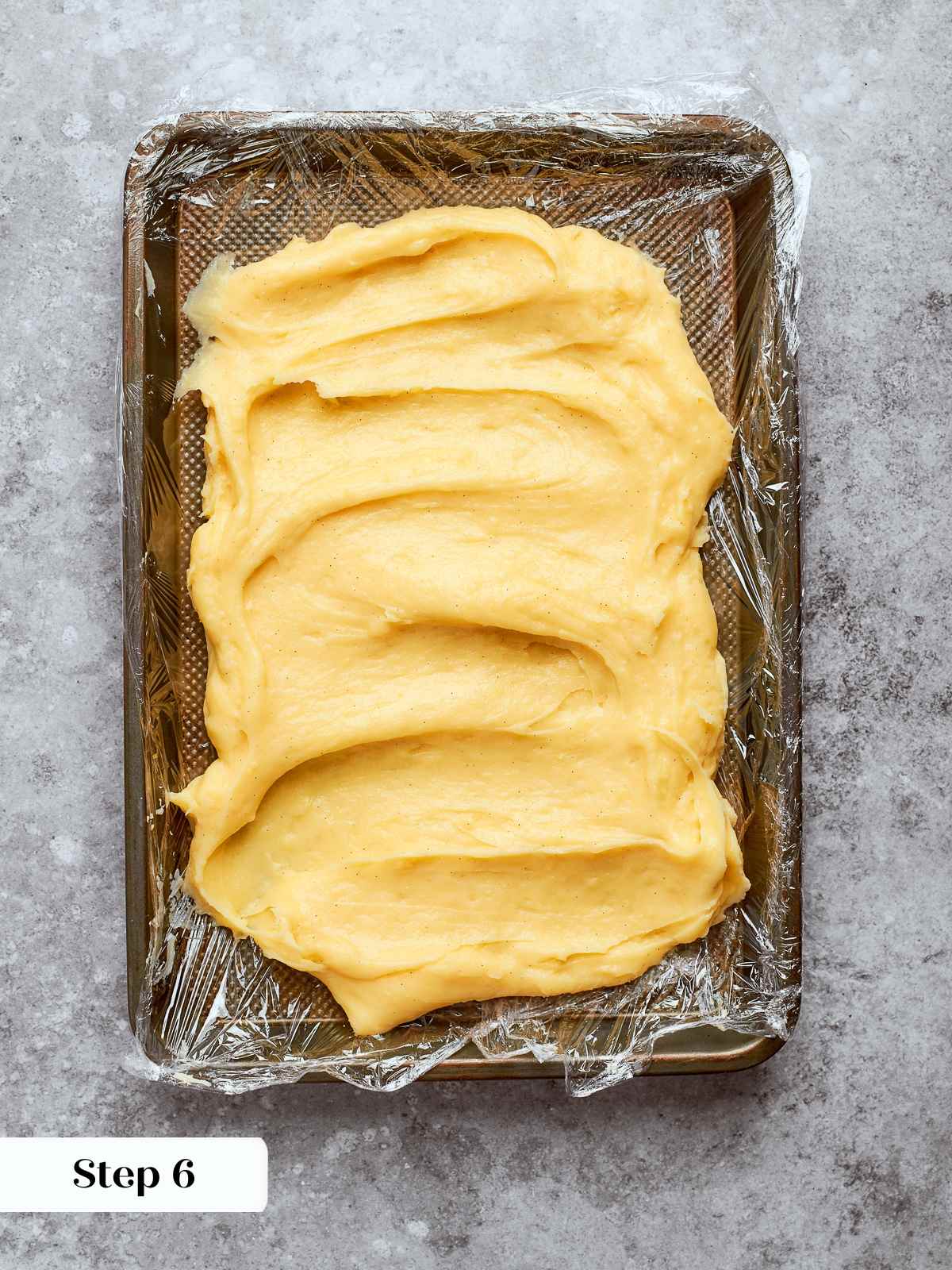 Freshly cooked pastry cream spread on lined sheet pan to cool quickly.