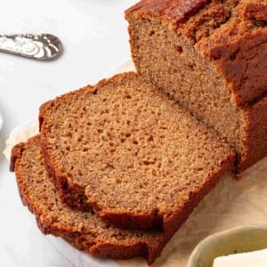 Tight square framing of the cut loaf and two slices showing tender cinnamon-flecked crumb in detail.