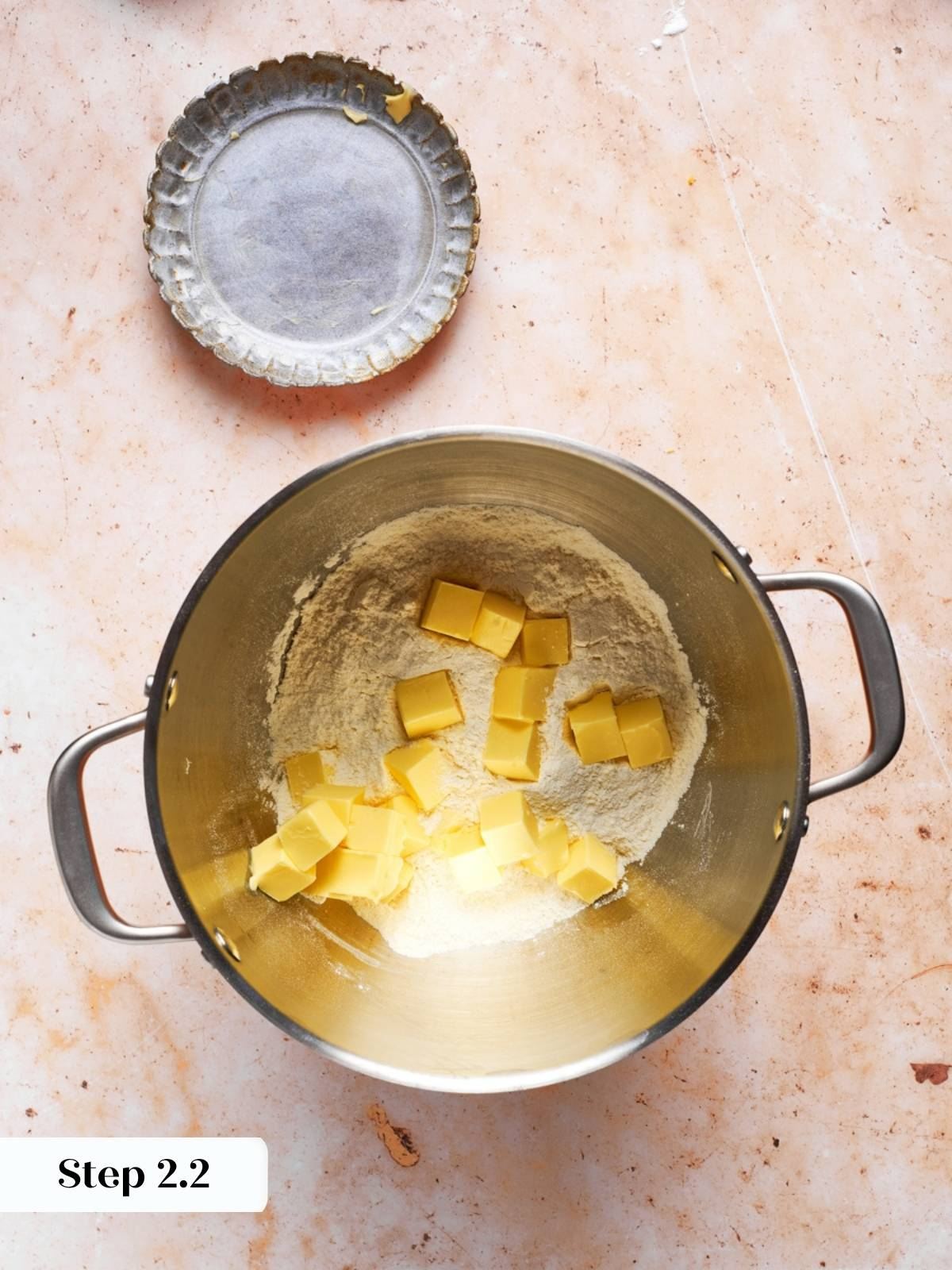 Cold butter cubes scattered over flour in a stand mixer bowl for the blueberry scones recipe.