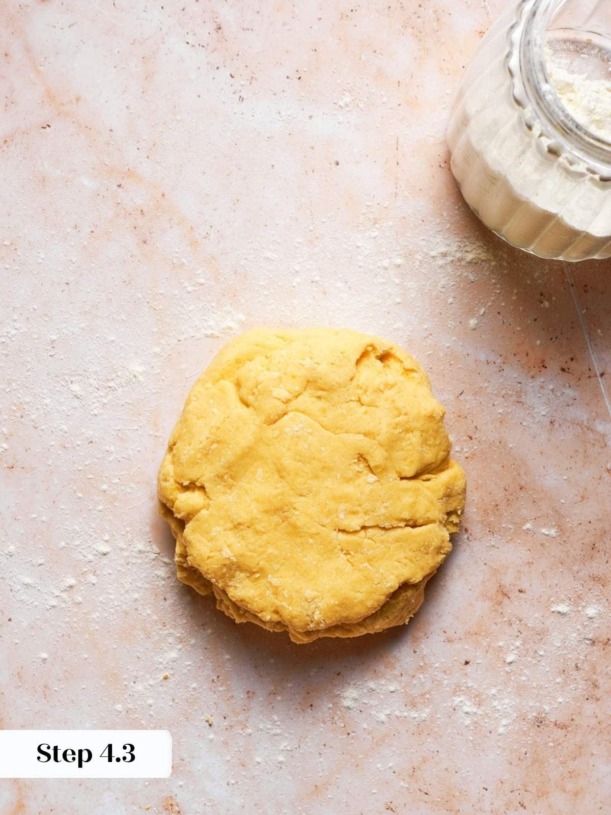 Kneaded dough patty resting on a pink surface, the next step in our blueberry scones recipe.