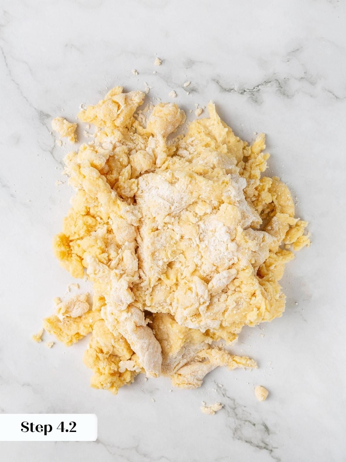 Crumbly scone dough turned out onto a marble counter with no visible dry spots remaining yet.