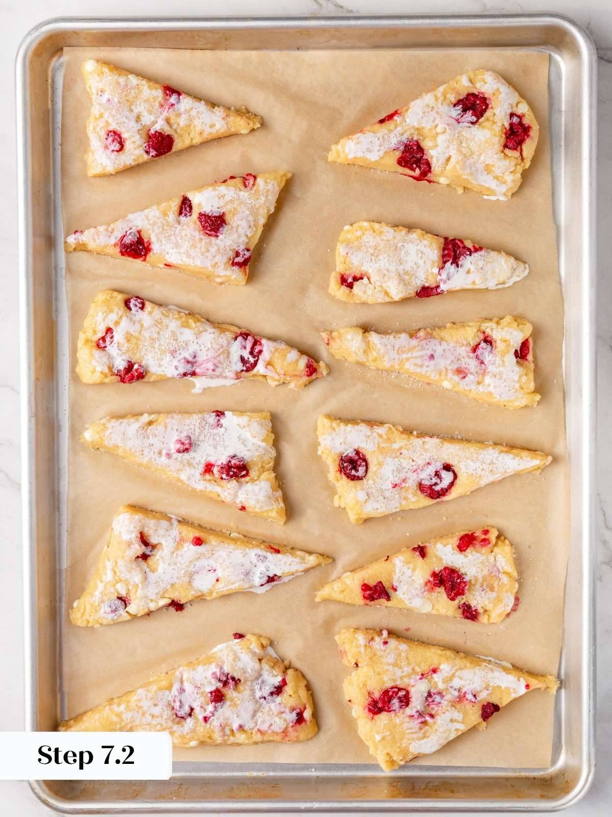 Twelve unbaked scones brushed with cream and sprinkled with sparkling sugar on a parchment-lined baking sheet.